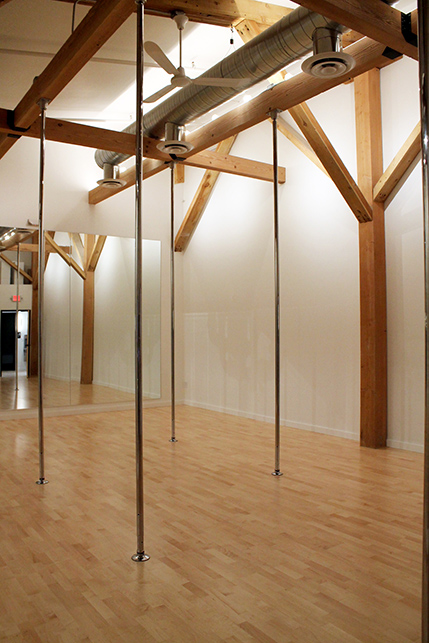 Fitness poles extend from exposed ceiling beams - exposed stainless steel ductwork gives a light industrial feeling